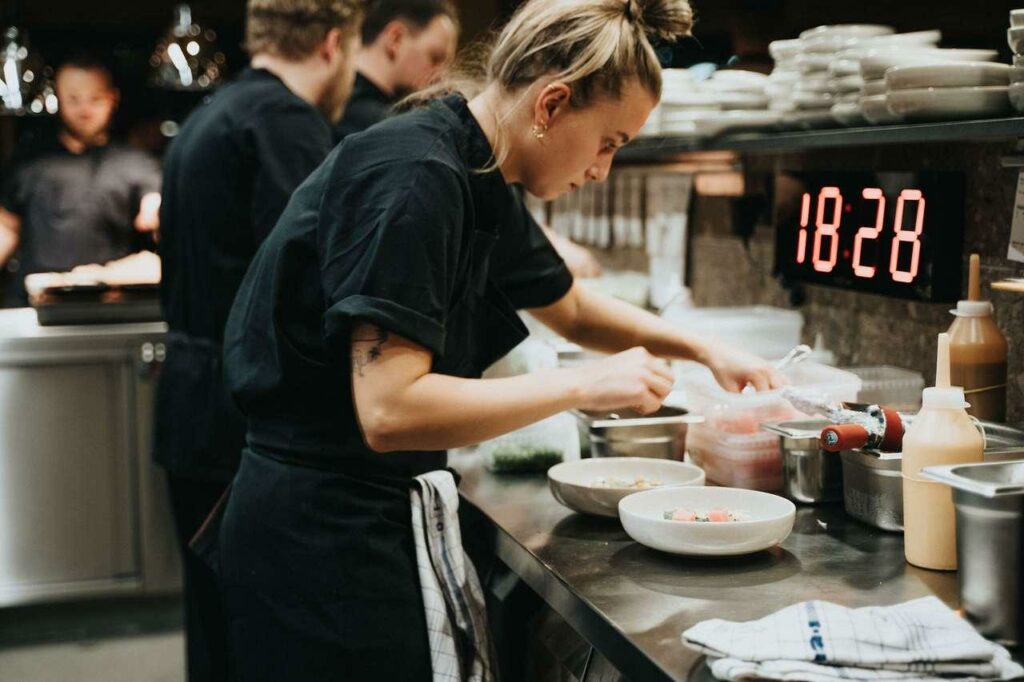 Équipe de restaurant en plein service avec suivi des horaires de travail, illustration des règles relatives au temps de travail dans les HCR et à la gestion de la paie.
